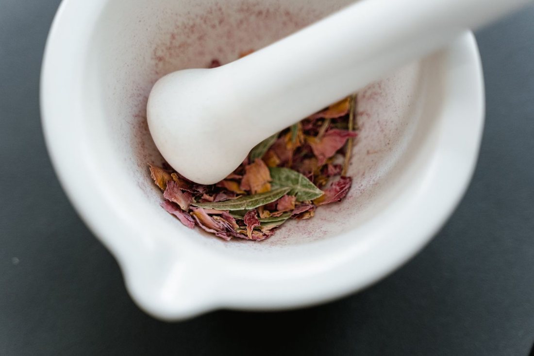 A stone mortar and pestle with dried herbs